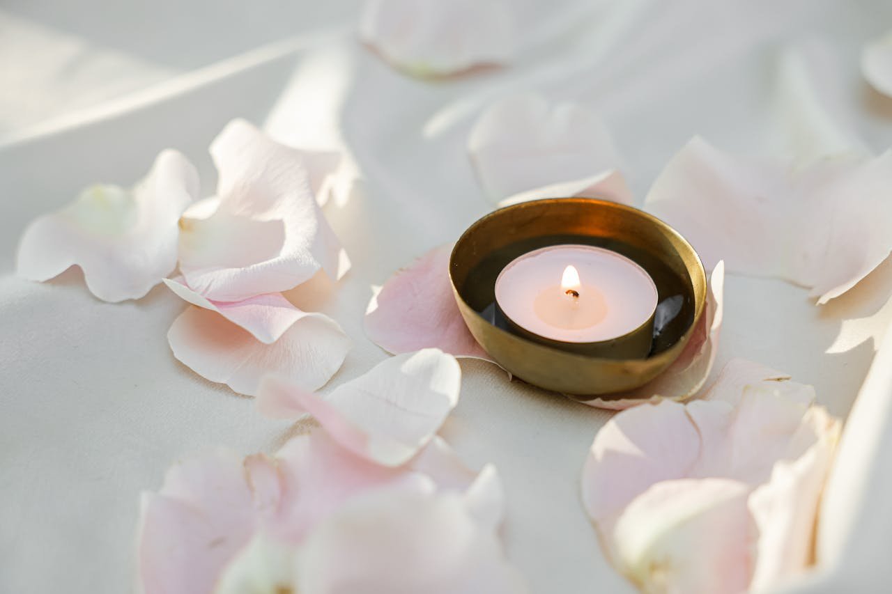 Relaxing scene with a lit candle and pink petals, perfect for aromatherapy enthusiasts.